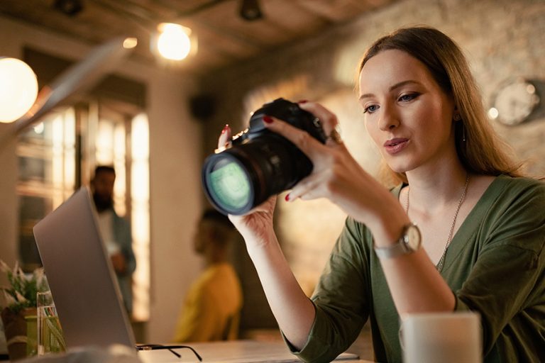 Young Woman with Camera on laptop - digital vs traditional marketing